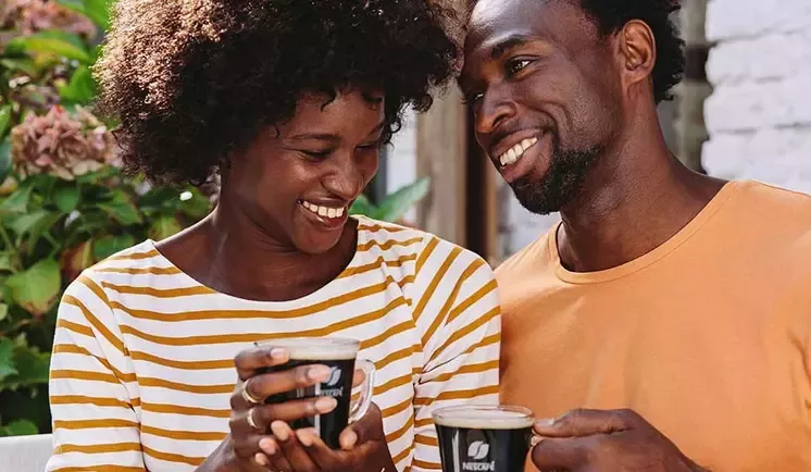 un couple souriant tenant une tasse de café